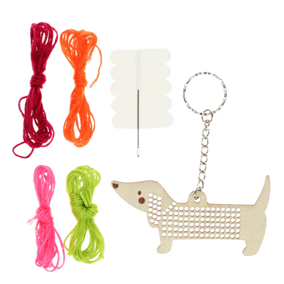 Dog toy set with colorful strings, a needle, and a dachshund-shaped keychain on a white background