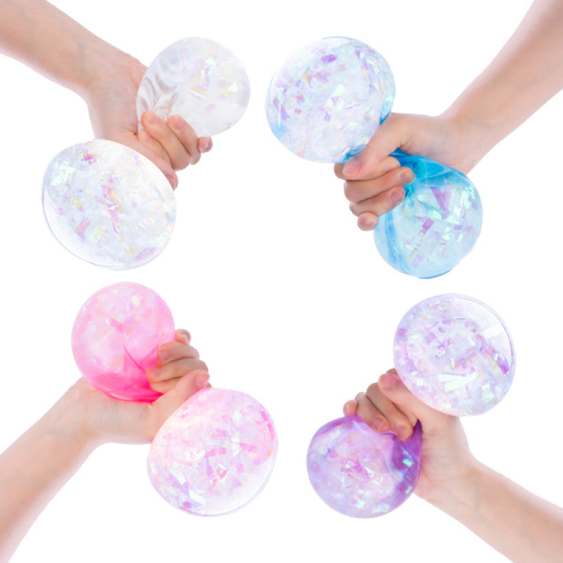 Hands holding colorful, translucent Smooshos Jumbo Crystal balls with confetti-like contents against a white background