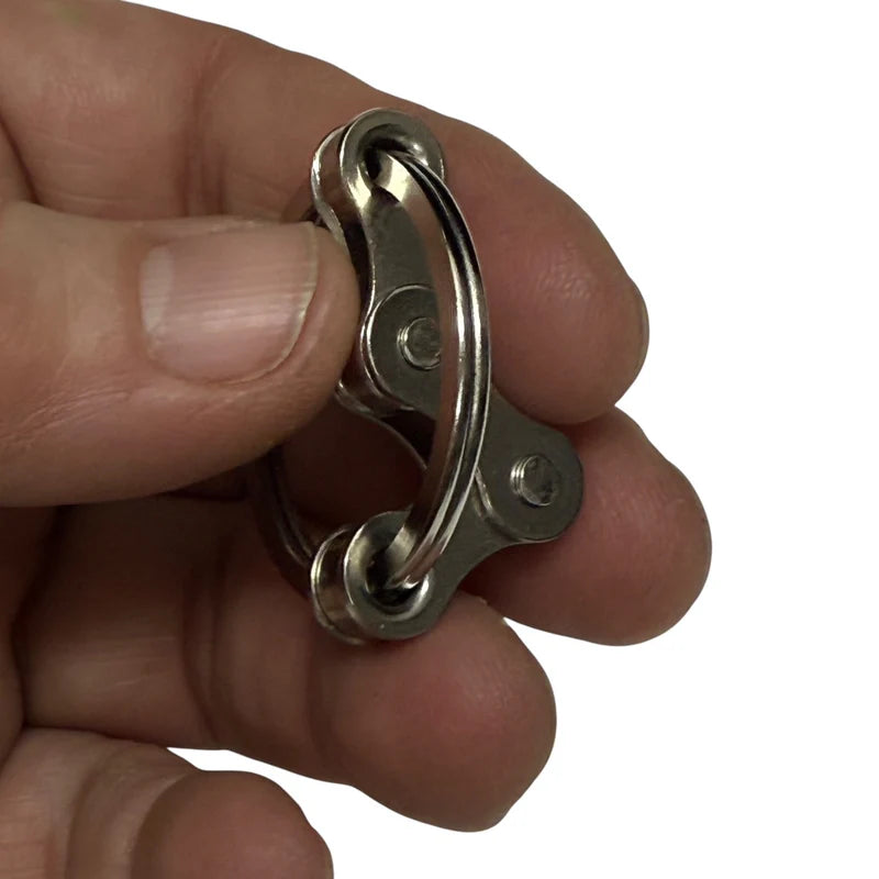 Kaiko Small Fidget  Silver chain and circle  held between fingers against a white background