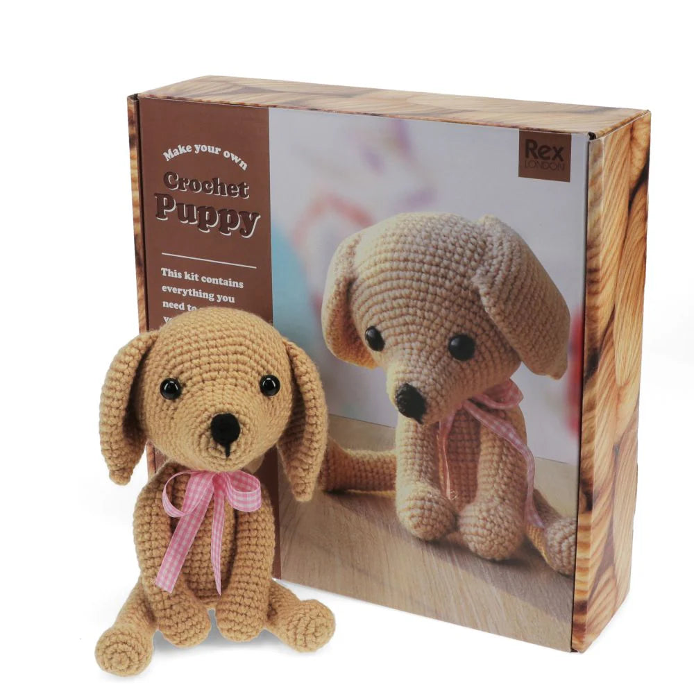 Crocheted puppy toy from Rex London in front of its packaging box