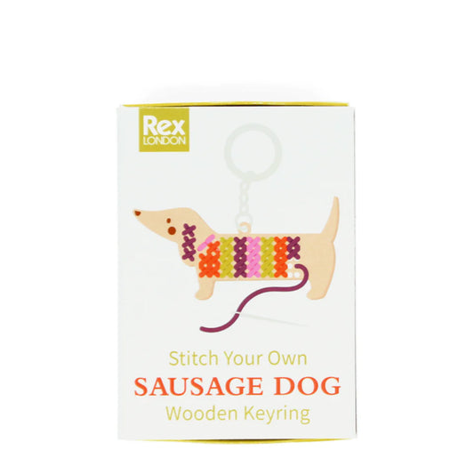 Packaging of a 'Stitch Your Own Sausage Dog' wooden keyring from Rex London on a white background.