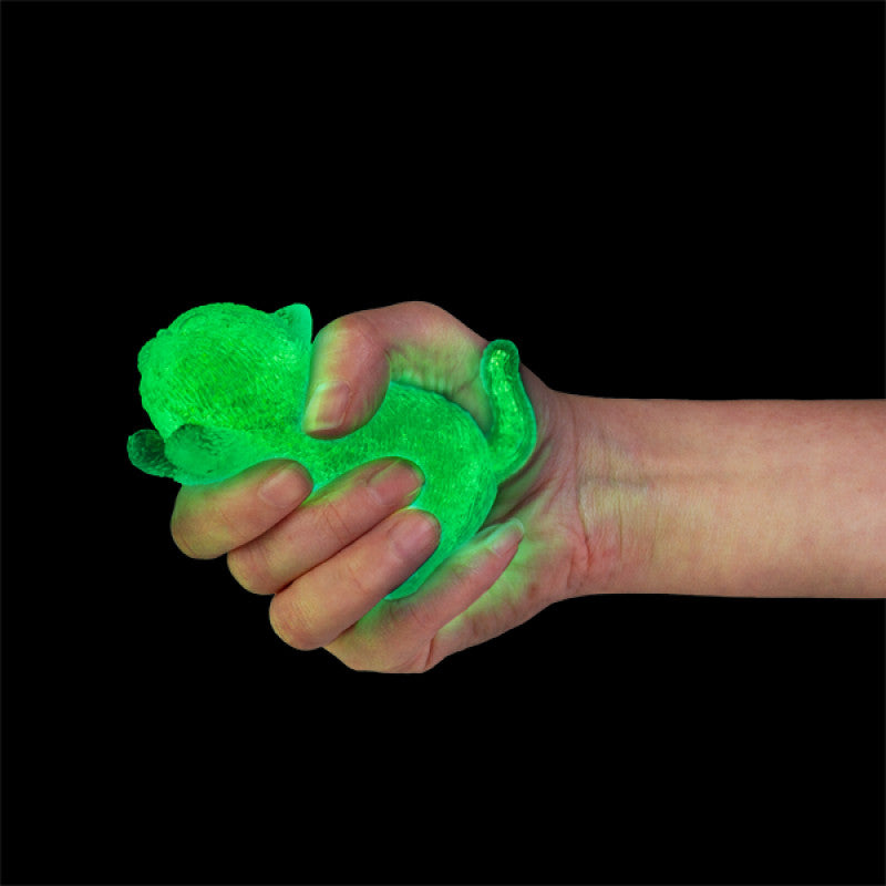 Green glowing Smooshos Super Squeeze Glow in the Dark Cat held in a hand against a black background