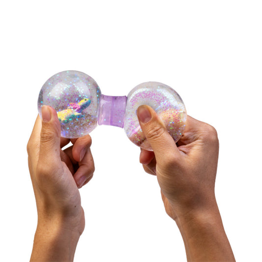 Two hands holding a glittery, Smoosho's Axolotl Dumbbell with a purple band against a white background