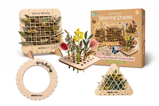 A white background with the contents of the weaving kit in the foreground. The contents are four wooden frames that string can be attached to to weave flowers into. Some frames in the image have flowers in them. The box the kit comes in is also in the image, and is brown cardboard.